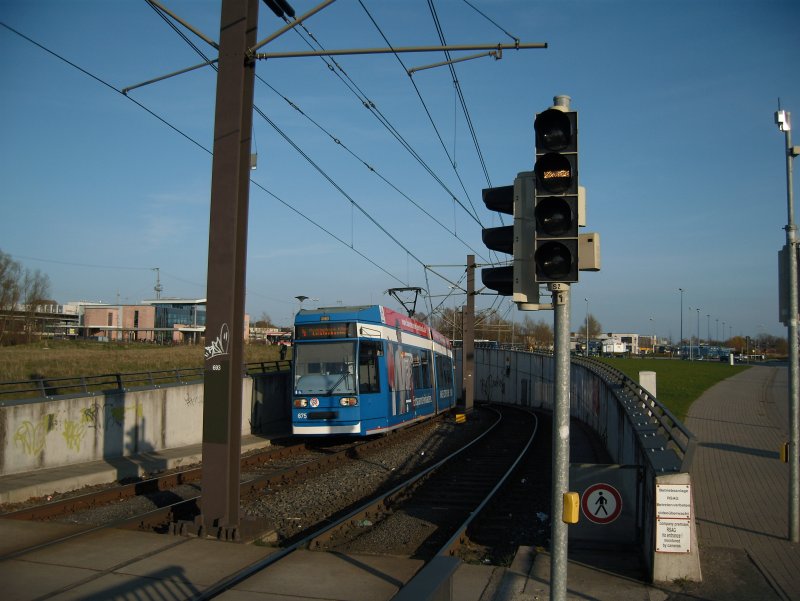 NGT 675 (6NGTDWE) verlsst den Tunnel unter dem Hauptbahnhof und fhrt dann in die Haltestelle  Platz der Freundschaft  ein. Im Hintergrund erkennt man das sdliche Empfangsgebude des Hbf's
Rostock 09.04.09