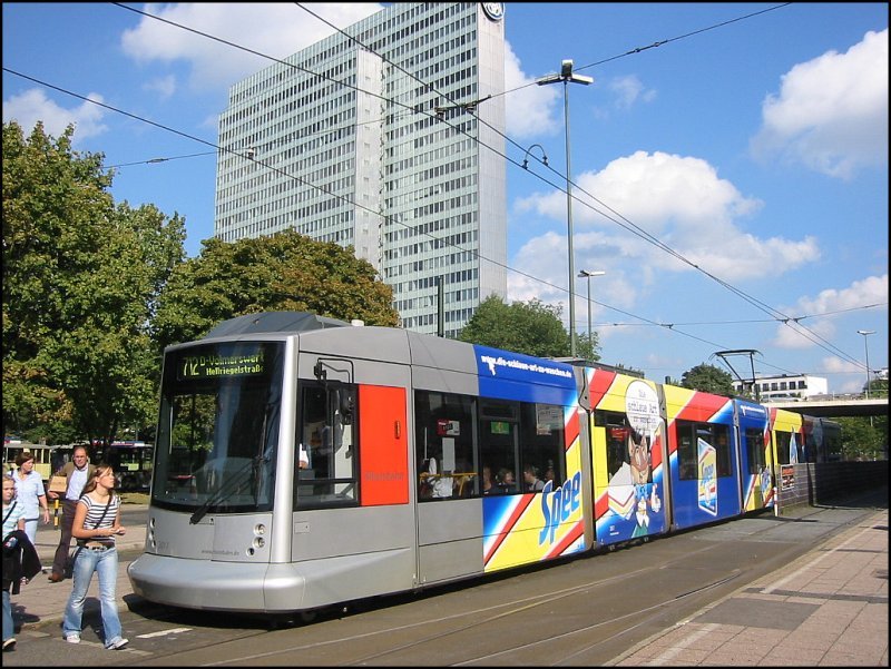 Niederflur-Straenbahnwagen 2017 der Rheinbahn vom Typ NF10 (Baujahr 2001), eingesetzt auf der Linie 712, steht gerade an der Haltestelle am Jan-Wellem-Platz. Auch hier wieder einmal eine recht farbenreiche Werbung, die teilweise ber die Fenster geht. Aus eigener Erfahrung kann ich aber sagen, dass die Beeintrchtigung der Sicht der Fahrgste an solchen Fenstern weniger schlimm ist als man zunchst denken mag. (30.09.2006)
