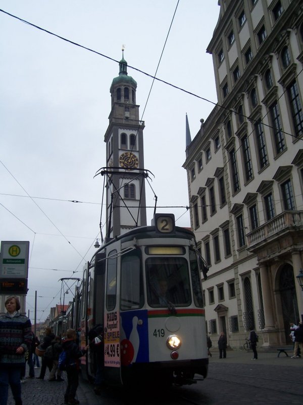 Noch bis voraussichtlich Sommer 2009 sind in Augsburg die legendren GT4 anzutreffen. Bis zum Ende der Combino-Sanierung leisten 8 Wagenpaare Verstrkerdienste in der werktglichen Hauptverkehrszeit. Die 20 GT4 der Augsburger Serie 411-420 ('fhrende Triebwagen' und 451-470 ('gefhrte Triebwagen') wurden 1995/96 aus Stuttgart bezogen und bei der MGB (Mittenwalder Gertebau GmbH) einer optischen und technischen Vollrekonstruktion unterzogen. Hier ein Zug der Linie 2 (Augsburg West - Zentralklinikum - Wertachbrcke - Rathausplatz - Knigsplatz - Haunstetten Nord) an der Haltestelle Rathausplatz, Augsburgs 'guter Stube'. Im Hintergrund Perlachturm und Rathaus, beides Wahrzeichen der Stadt. Typisch fr die Augsburger GT4 in den letzten Einsatzjahren sind die Steckschilder in der Fahrerkabine, da durch Liniennderungen im Jahr 2006 die Liniennummern nicht mehr mit den Endhaltestellen im Rollbandkasten bereinstimmen. Aufnahme 30. Oktober 2008.