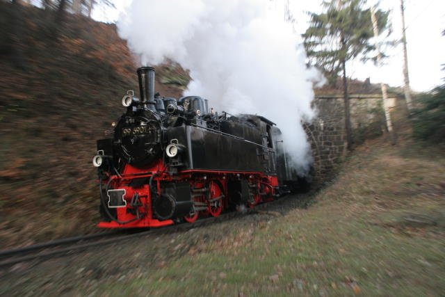 Noch einmal ein Foto von 99 5901 bei der Ausfahrt aus dem Tunnel Thumkuhlenkopf. Ein Mitf�hren des Drehzooms in der gleichen Geschwindigkeit der Lokomotive bei einer geringen Belichtzeit und einer Reihenbildfolge von 5 Bilder/Sek. verzerrt die Landschaft und l�sst die Geschwindigkeit des Zuges erahnen. Der Effekt ist �hnlich der Mitf�hrtechnik bei seitlichen Aufnahmen im Automobilsport.
Der Effekt passierte mir bei der Suche nach dem  perfekten Treffer  eher zuf�llig und ist Geschmacksache.
