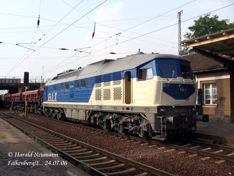 Obwohl es  E.i.LT , schleicht 232 037 hier mit ihrem Zug durch Falkenberg(Elster). Grund: Die RB nach Dessau kreuzt beim Ausfahren gerade den Weg.