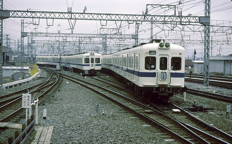 Odakyû-Konzern (1067 mm Spur, Gleichstrom 1500 V). Rechts Serie 2200 (Nr. 2224); die Wagen dieser Serie sind noch 17,5m lang und wurden 1954-1958 erbaut. Es sind die ersten Hochleistungstriebzüge des Odakyû-Konzerns und bilden die Grundlage für viele weitere Serien. Sie bildeten 2- und 4-Wagenzüge. Die letzten waren bis 1984 im Einsatz. Links Serie 5000 (1.Generation), jetzt 20 Meter lang, 1969-1982 erbaut. Es gab 4-, 6- und 8-Wagenzüge. Die letzten schieden 2012 aus. Links im Bild Zug 5161. Odawara, 4.Dezember 1979.  