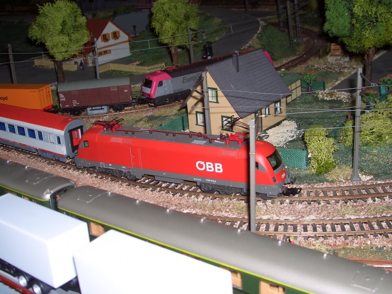 BB 1116-174-2 Taurus mit EC-Waggons verlsst gerade den Bahnhof Neuenfeld. Im Hintergrund steht BR 127-001-6 mit ihrem Gterzug und wartet auf das Abfahrtssignal