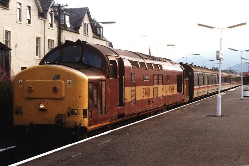 Pers�nlich bin ich ein gro� Liebhaber von diese Dieselloks der Class 37 mit runde Nasen. Gl�cklich gab es noch einige Loks in Fort Willian bei meinem Besuch an Schottland in 1999. Hier ist die 37411 mit Zug Fort William-Glasgow auf Bahnhof Fort William am 31-07-1999. Bild und scan: Date Jan de Vries.