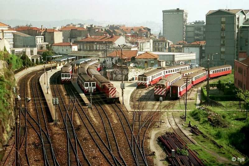 Porto Est. Trindade am 11. Mai 1988. Trindade war der Schmalspurbahnhof im Zentrum von Porto. Hier starteten die Zge nach Guimares und nach Pvoa de Varzim. Auf den Gleisen sind alle zur Zeit der Aufnahme eingesetzten Fahrzeugtypen versammelt: dieselelektrische Triebzge der BR 9600, Diesellokomotiven der BR 9000 (rechts) und 9020 (Mitte) sowie in Italien gebaute Stahl-Vierachser von 1931. - Das Meterspurnetz von Porto existiert nicht mehr. Einige Strecken wurden in das Netz der normalspurigen Stadtbahn  Metro do Porto  einbezogen.