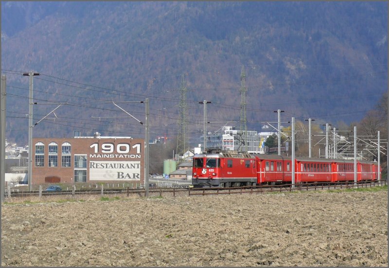 RE 1248 nach Disentis am Stadtrand von Chur mit der Ge 4/4 II 625  Kblis . Das Gebude im Hintergrund ist nicht der alte Hauptbahnhof und hat nichts mit der Bahn zu tun. Das Restaurant ist mit ffentlichen Verkehrsmitteln, speziell am Abend nicht erreichbar, was vermuten lsst, dass dort nur Mineralwasser getrunken wird. (31.03.2008)