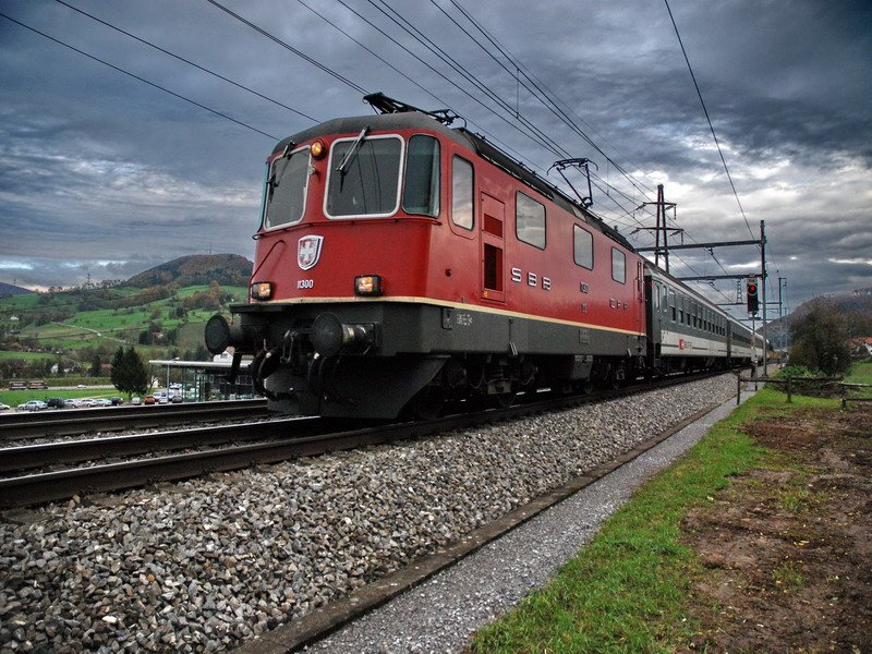 Re 4/4 11300. Der InterRegio hat vor 1 Min. den Bahnhof Frick im Kanton Aargau verlassen und wird in knapp 30 Min. in Basel SBB sein. Auch an einem regnerischen Tag lassen sich noch interessante Aufnahmen machen. Nikon D80, 18mm (27mm bei KB) ,ISO 800 - deshalb leichtes Rauschen, Blende 3,5 - 1/1250s - die schnelle Zeit braucht man schon fr ein scharfes Bild. 13.11.2006