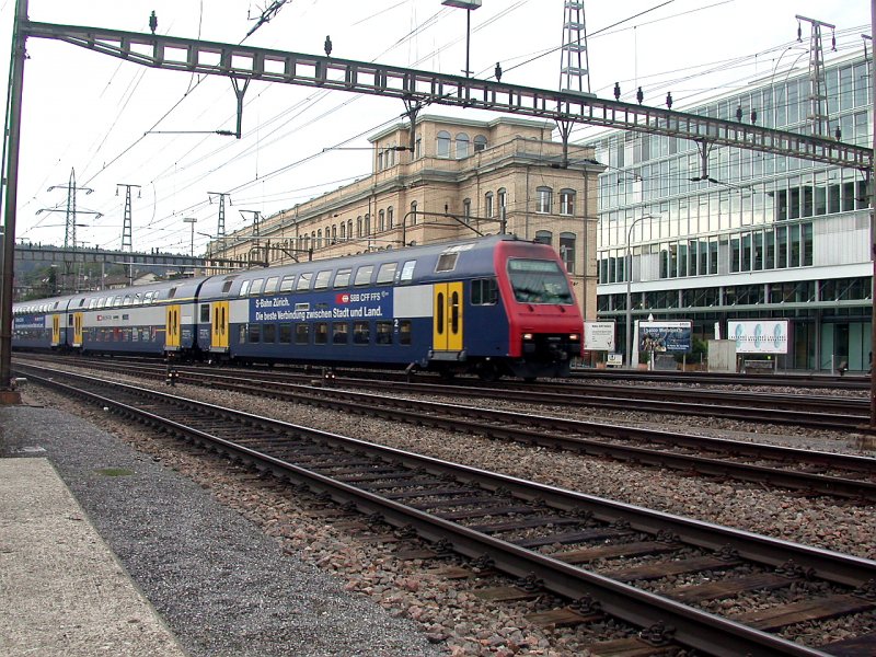 Re 450 Doppelstockpendel der S-Bahn Zrich fhrt in den Bahnhof Oerlikon ein. Im Hintergrund noch ein Teil der ehemaligen Maschinenfabrik Oerlikon, in dem sich heute eine Bistrobar namens Gleis 9 befindet. (03.10.2006)