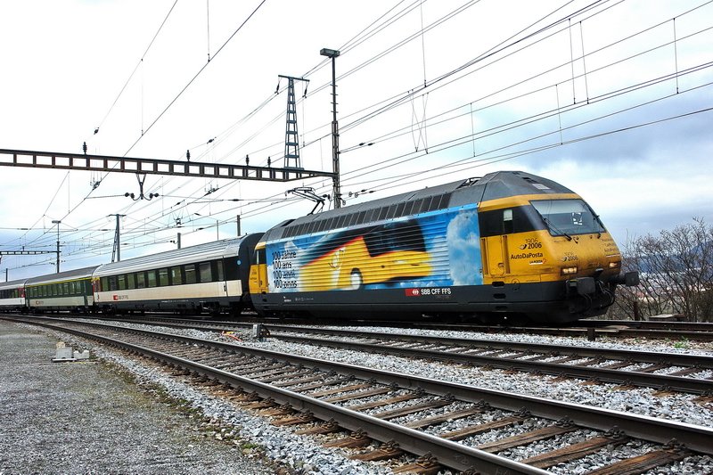 Re 460 006-0. Einfahrt des InterRegio nach Zrich in den Bhf. STEIN Sckingen (Kanton Aargau) am 24.3.2007 bei wolkenverhangenem Himmel.  100 Jahre Postauto  lautet die Werbung auf der gelben Werbelok, der eine Wsche nicht schaden wrde.  