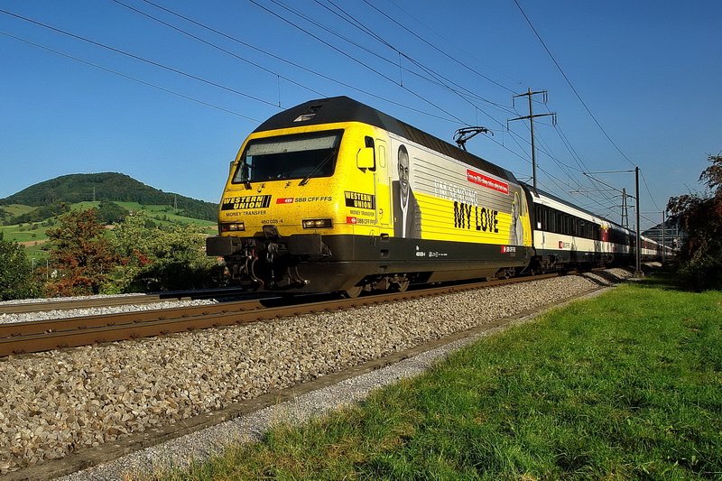 Re 460 028-4. Das Licht am spten Nachmittag lsst das knallige Gelb der Western Union Werbelok hell erstrahlen. Der InterRegio ist auf der Fahrt nach Basel. Im Fricktal ( Aargau ) am 27.8.2007