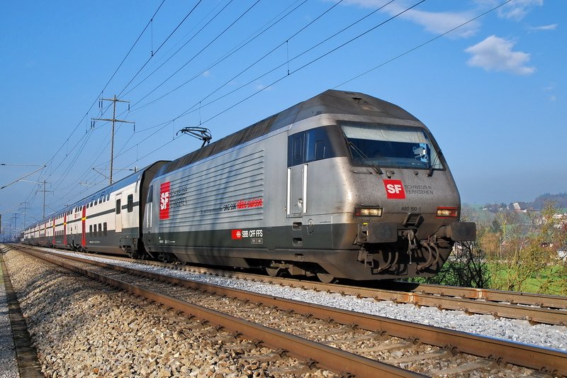 Re 460 100-1. Na bitte, das Warten hat sich gelohnt (siehe Bild ID 78127). Die Sonne scheint noch immer und sorgt fr ein schnes Foto der silberfarbenen  SF Schweizer Fernsehen  Werbelok. Der IR2075 von Basel kommend erreicht gleich den Bahnhof Frick (Kanton Aargau). ber Brugg AG und Baden geht es weiter nach Zrich. 3.12.2006