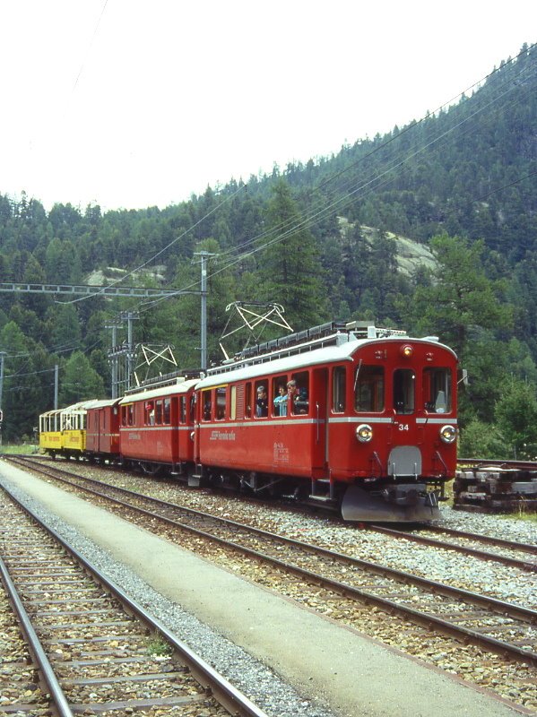 RhB Aussichtswagen-Extrazug 3962 fr RHTIA TOURS von Alp Grm nach Pontresina am 30.08.1996 in Morteratsch mit Triebwagen ABe 4/4 I 34 - ABe 4/4 I 30 - D 4035 - B 2093 - B 2097. Hinweis: Die beiden Triebwagen sind inzwischen in gelb umlackiert, hier das Problem des Extrazuges 3962 mit berlnge auf Gleis 3 mit gleichzeitiger berholung durch Zug 464 und Kreuzung durch Zug 441, gescanntes Dia.

