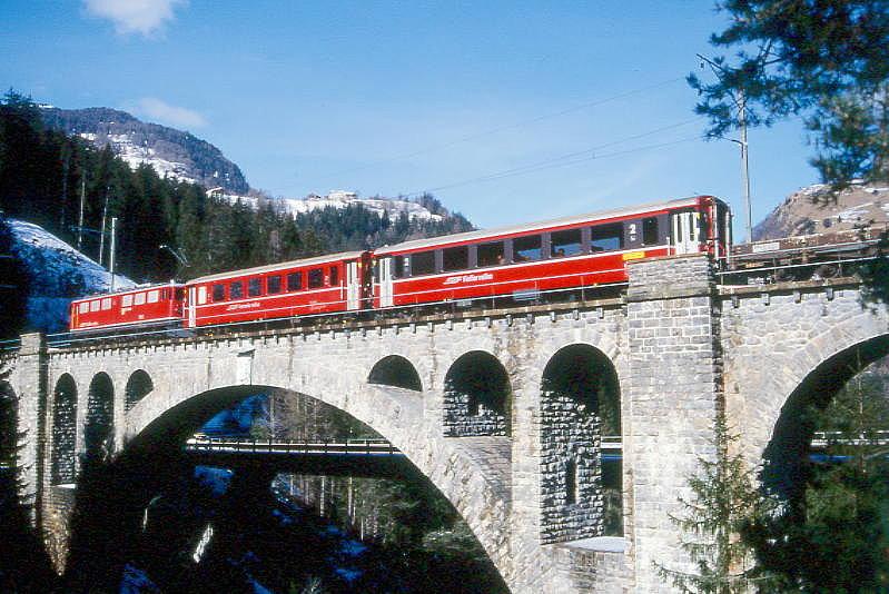 RhB Autozug A1534 von Samedan nach Thusis am 26.02.2000 auf Soliser Viadukt mit E-Lok Ge 6/6II 703 - B 2451 - B 2467 - 8x Sklp/Rw. Hinweis: gescanntes Dia

