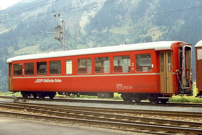 RhB - B 2211 am 01.10.1990 in Disentis - 2.Klasse Leichtstahlwagen, geeignet fr Krankentransporte der Armee - Baujahr 1913 - SIG - Fahrzeuggewicht 19,00t - Sitzpltze 64, Stehpltze 20 - LP 15,77m - zulssige Geschwindigkeit 90 km/h - mit eingebauten Bremszahnrad - 3=15.06.1984 2=06.07.1990 - Lebenslauf: ex C4 2211 - 1930 C4 2211 - 1956 B4 2211 - 1960 Sanittswagen - 1964 B 2211 - 04/2005 Kasten an Hotel Bellaval in St.Moritz - Logo RhB in deutsch. Hinweis: Griffstangen neben den Tren, Klassezahlen klein, flacher Anschriftenblock, dnne Betriebsnummern.
