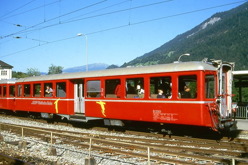 RhB - B 2301 am 24.08.2000 in Reichenau - 2.Klasse Mitteleinstiegs-Personenwagen Fliegender Rhtier - bernahme 1938 - SWS/SIG - Fahrzeuggewicht 18,00t - Sitzpltze 64 - LP 17,73m - zulssige Geschwindigkeit 90 km/h - 2=26.11.1992 1=11.05.2000 - Logo RhB in deutsch - Lebenslauf: ex C4 2301 - 1956 B4 2301 - 1964 B 2301 - Snowbordwagen mit Logo
