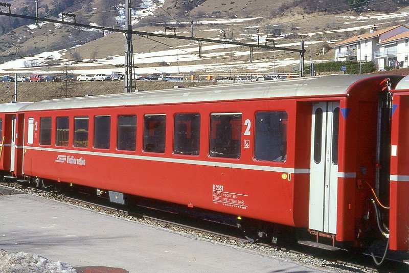 RhB - B 2351 am 13.03.2000 in Scuol - 2.Klasse Einheitspersonenwagen (Typ 1) - bernahme 19.06.1964 - FFA/SIG/RhB - Fahrzeuggewicht 21,00t - Sitzpltze 60 - LP 18,42m - zulssige Geschwindigkeit 90 km/h - Logo RhB in rtoromanisch - 3=02.12.1994 1=25.06.1999 - Lebenslauf: ex B4 2351 - 1964 B 2351 - Hinweis: Klassezahlen gro, hoher Anschriftenblock, dicke Betriebsnummern, Griffstangen neben den Tren entfernt - blaue Kennzeichnung an den Ecken - die Fahrzeugserie besteht aus 33 Wagen mit den Nummern 2341 bis 2373. 
