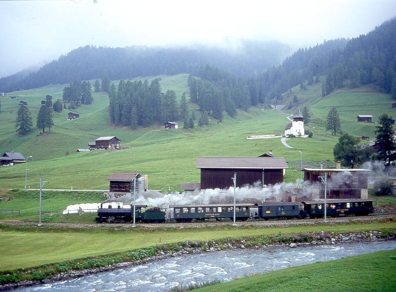 RhB Dampf-Extrazug fr RHTIA INCOMING von Davos-Platz nach Filisur vom 27.08.1995 bei Davos-Frauenkirch mit Dampflok G 4/5 108 - B 2247 - D 4052I - B 2246. Hinweis: Blick Richtung Kapelle von Frauenkirch, leider ist durch Neubauten die Landschaft nicht mehr so fotogen wie frher, geschickt versteckt befindet sich eine hohe hliche Betonmauer direkt hinter der Zuggarnitur.