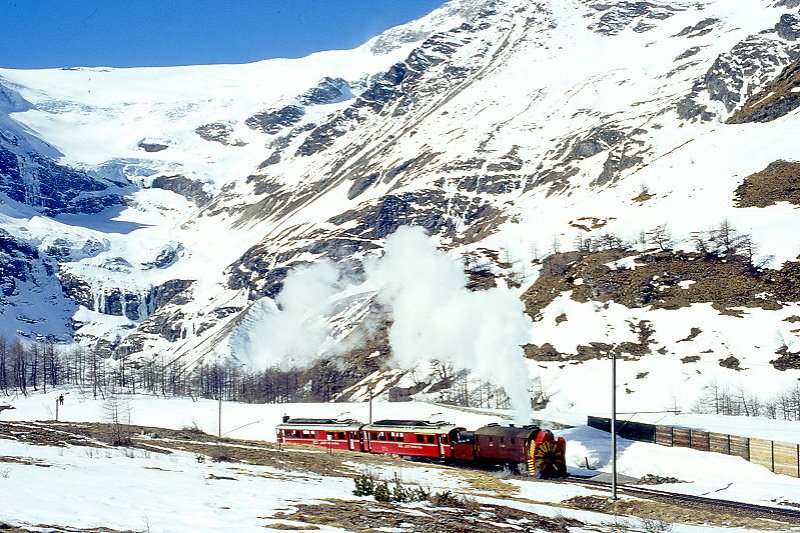 RhB - Dampfschneeschleuderextrazug 9462.2 fr Graubnden Tours von Alp Grm nach Ospizio Bernina am 28.02.1998 oberhalb Alp Grm mit Dampfschneeschleuder X d rot 9213 - Triebwagen ABe 4/4 I 30 + ABe 4/4 I 30. Hinweis: Blick links oben auf Pal-Gletscher, Triebwagen verkehren heute in gelber Lackierung, gescanntes Dia.
