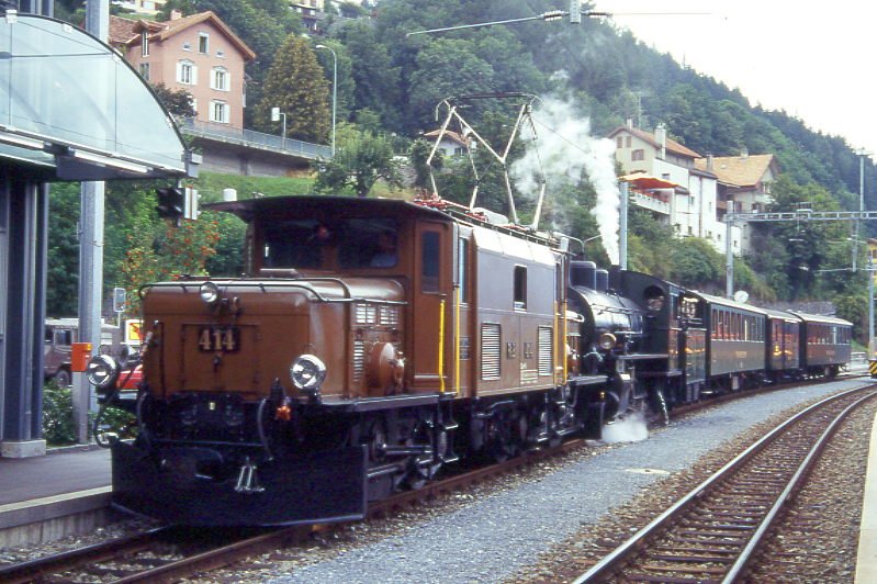 RhB Dampfzug 3549 fr RHTIA INCOMING von Thusis nach Bergn am 24.08.1995 in Thusis mit E-Lok-Vorspann Ge 6/6 I 414 - G 4/5 107 - B 2247 - D 4052I - B 2246. Hinweis: Krokodil aus Sicherheitsgrnden mit aptierten Pantografen, gescanntes Dia
