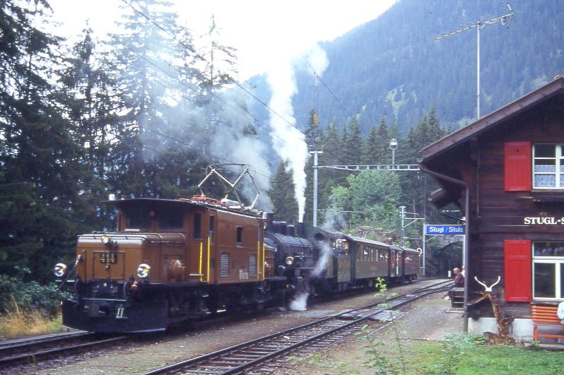 RhB Dampfzug 3549 fr RHTIA INCOMING von Thusis nach Bergn am 24.08.1995 in Stugl mit E-Lok-Vorspann Ge 6/6 I 414 - G 4/5 107 - B 2247 - D 4052I - B 2246. Hinweis: Krokodil aus Sicherheitsgrnden mit aptierten Pantografen, gescanntes Dia

