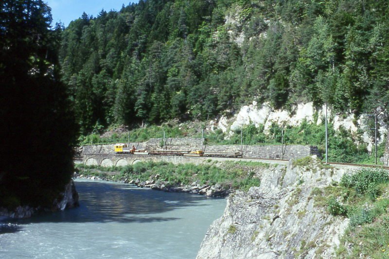 RhB Dienstzug 9251 von Reichenau nach Disentis am 01.09.1997 bei der Hochwassermarke zwischen Reichenau und Trin mit Traktor Tm 2/2 81 - Kkw 73xx - Rw 8244 - Kw 7506 - Rpw 8233 - Hinweis: Notbrckentransport mit Schutzwagen zwichen den Ladungen fr Baustelle Sedrun, gescanntes Dia
