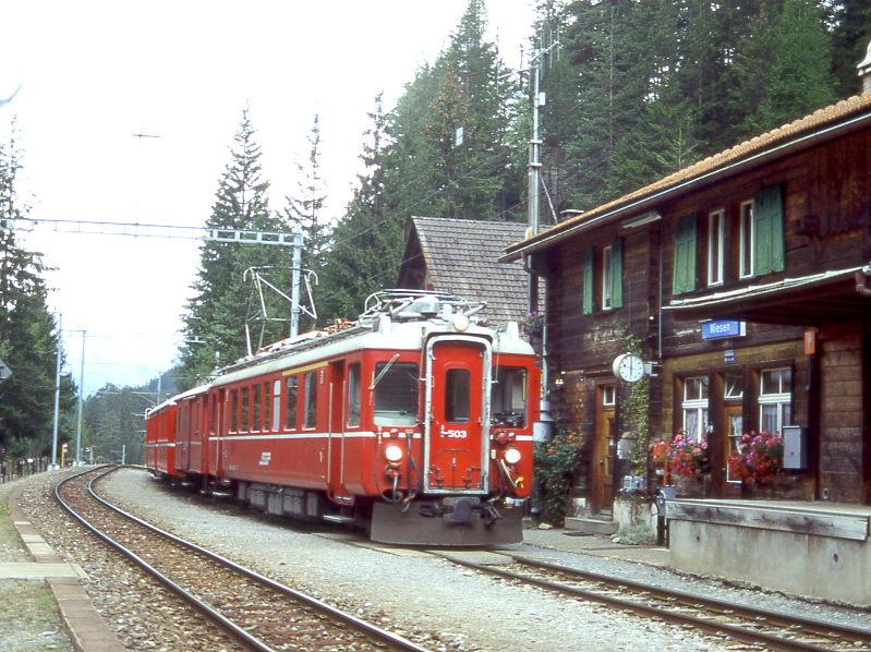 RhB Extrazug FLIEGENDER RHTIER fr RHTIA TOURS 3574 von Bever nach Davos-Platz vom 29.08.1996 in Wiesen mit Triebwagen ABe 4/4 503 - D 4054 - B 2301 - A 1252. Hinweis: Blick vom Wanderweg zum Wiesener Viaduht auf hlzernes Bahnhofsgebude von Wiesen. Triebwagen wurde 1998 in Steuerwagen umgebaut, nach mehreren Probefahrten im Juni 1998 abgebrochen!

