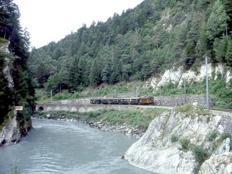 RhB Extrazug fr GRAUBNDEN TOURS 3238 von Disentis nach Landquart vom 30.08.1997 bei der Hochwassermarke zwischen Trin und Reichenau mit E-Lok-Oldtimer Ge 2/4 222 - B 2247 - B 2246 - D 4052I. Hinweis: Links an der Felswand ist an der hellen Tafel die Hochwassermarke des Vorderrheins angebracht. Hier in der Vorderrheinschlucht ist auch der engste Kurvenradius mit 100m der Bahnlinie sichtbar.