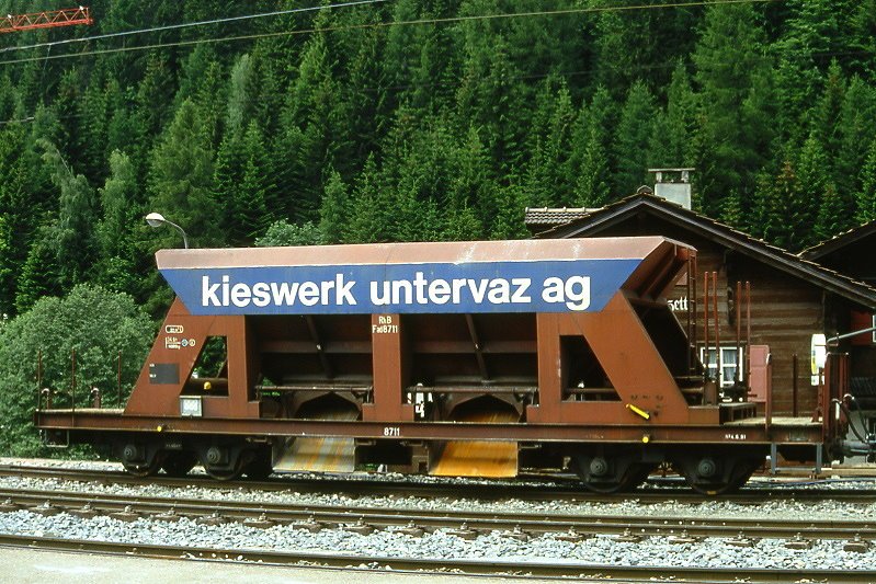 RhB - Fad 8711 am 10.06.1993 in Klosters - Selbstentladewagen 4-achsig mit 1 offenen Plattform - Werbung: Kieswerk Untervaz AG - JMR - Gewicht 14,08t - Zuladung 34,50t - LP 12,50m - zulssige Geschwindigkeit Aufkleber 70/B km/h - 2=04.06.1991 - Lebenslauf: ex Fad 8711 - 02/2005 Fac 8711.
