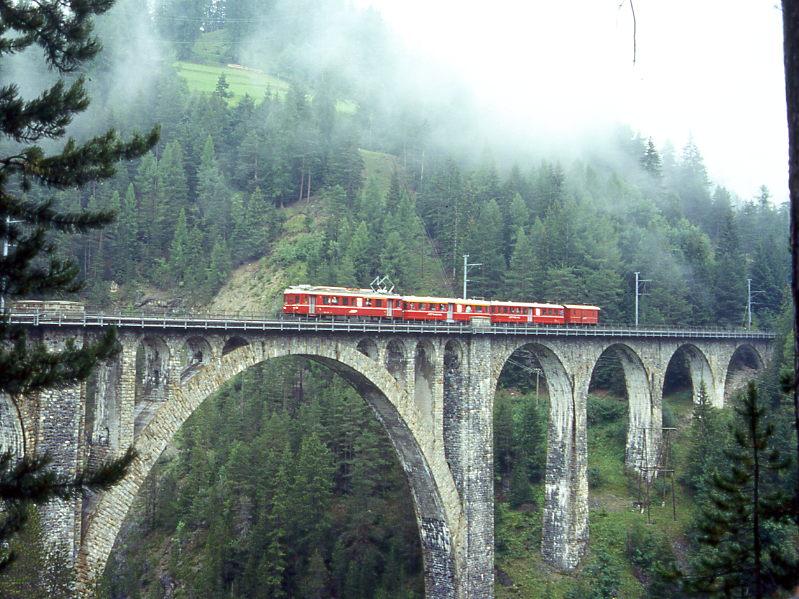 RhB FLIEGENDER RHTIER-Extrazug 3125 von Davos-Platz nach Pontresina vom 30.08.1996 auf Wiesener Viadukt mit Triebwagen ABe 4/4 503 - A 1252 - B 2301 - D 4054. Hinweis: Diese Kompo wurde als Fotozug zusammengestellt mit den Originalfahrzeugen, die als Leichtschnellzug ab 1940 zur Verkrzung der Krokofahrzeiten am Albula eingesetzt wurden. Die RhB beschaffte 1939/40 vier Leichttriebwagen 501 - 504, die beiden Leichtstahlwagen heute A 1251 und 1252 und sechs Leichtstahlwagen heute B 2301 bis 2306. Von den vier Triebwagen ist heute nur noch der ABe 4/4 501 als historisches Fahrzeug vorhanden. In den letzten Betriebsjahren war der Einsatz vorwiegend in Planpendelzgen im Engadin zwischen Zuoz und St.Moritz und zwischen Samedan und Pontresina. Fr die zwei Pendelzge wurden normalerweise zwei bis drei Triebwagen bentigt, einer war Reservefahrzeug in Samedan, Samstags auch als Gepckzug mit Gterwagen im Engadin unterwegs. Normalansicht von Sden