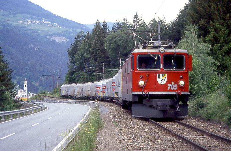 RhB Gterzug 5527 von Landquart nach St.Moritz am 03.06.1992 kurz nach Tiefencastel mit E-Lok Ge 6/6II 705 - 12 Uce. Hinweis: Zementzug, Uce teilweise noch alte Lackierung! Links ist die Kirche von Tiefencastel sichtbar. Zughakenlast ca. 275t, mehr volle Uce geht nicht!
