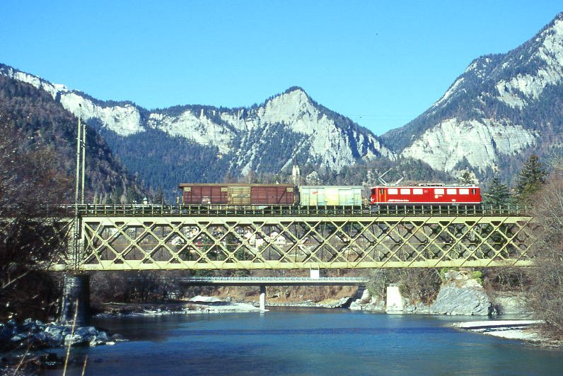 RhB Gterzug 5552 von St.Moritz nach Landquart am 27.02.1998 auf der Rheinbrcke bei Reichenau mit E-Lok Ge 6/6 II 701 - Gbkv - Gakv - 2x Xak - Gb - Kkw. Hinweis: Lok noch mit Scherenpantograf, hier ist der Zusammenfluss von Vorder- und Hinterrhein sichtbar. Abfluss ist nach rechts Richtung Bodensee, gescanntes Dia
