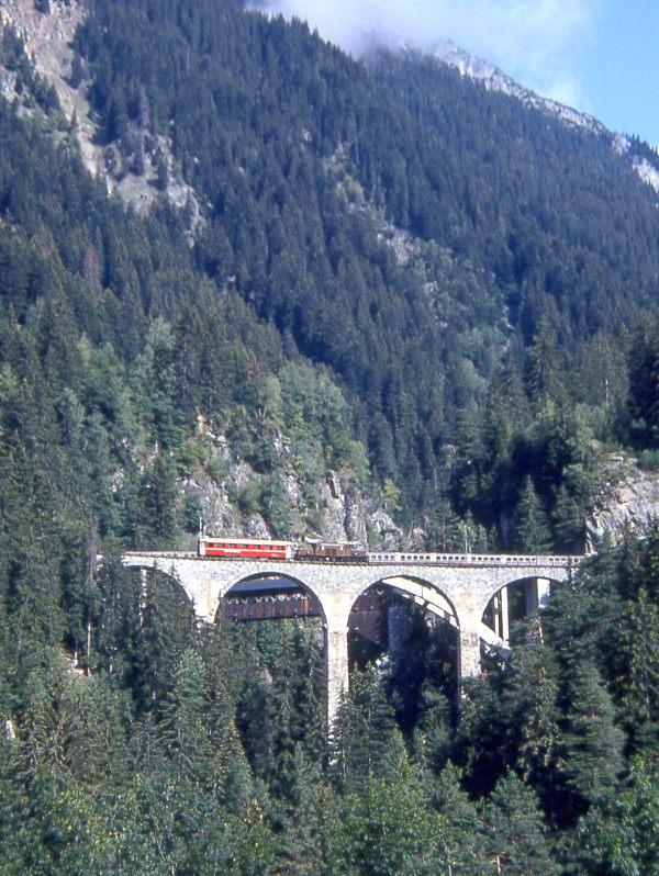 RhB Gterzug 5738 von Disentis nach Landquart vom 11.08.1992 auf Val Russein-Viadukt mit E-Lok-Oldtimer Ge 6/6I 415 - A 1254. Hinweis: Krokodil im Planeinsatz mit Gterzug noch ohne gesammelte Gterlast, der A-Klasse-Personenwagen wurde mitgefhrt weben weiblichen Rangierer! Der Steinviadukt wurde 1911 erbaut, Brckenmitte bei km 68,939 - Lnge 105,50 m - Hhe 56,50 m - 4 ffnungen je 20,00 m - 27 Promille Steigung. Aufnahme mit 300er-Tele 


