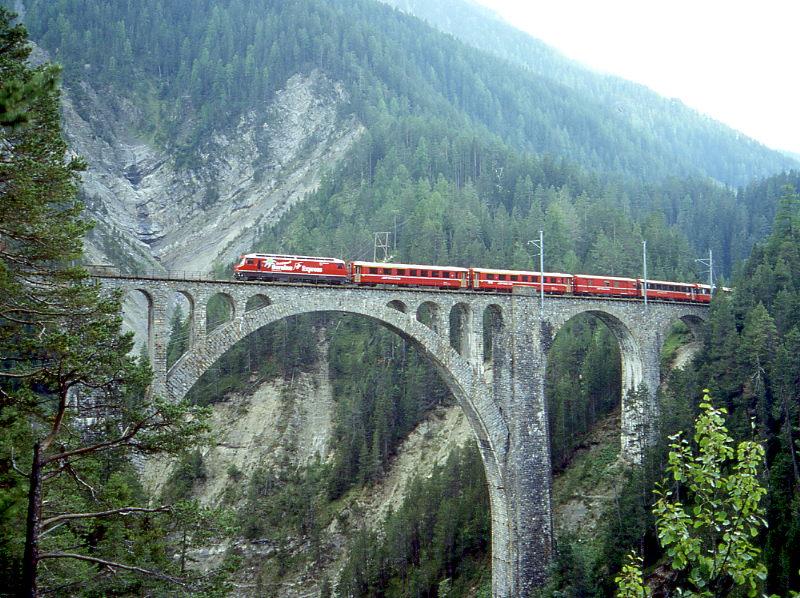RhB Heidiland-Bernina-Expre� H 502 von Tirano �ber Pontresina - Filisur - Davos-Platz nach Landquart vom 31.08.1996 auf Wiesener Viadukt mit Ge 4/4III 641 - AB - AB - D - B 2463 - A 1271 - B 2494 - B 2468. Hinweis: Normalerweise wird nie eine Lok Ge 4/4III f�r einen Berninaexpre� eingesetzt. Die RhB wollte jedoch f�r die vielen gut zahlenden teilnehmenden Fotografen bei einer 4-Tages-Fotofahrt etwas besonderes bieten und hat extra die Heidiland-Berninaexpress-Werbelok vor den zugeh�rigen Zug gespannt, blos der Wettergott hatte wie am Tag zuvor kein Einsehen! Ansicht von Norden (selten fotografiert), jedoch nur am sp�ten Nachmittag Sonne m�glich, mehrere Fotostellen von einen leicht erreichbaren befestigten Weg m�glich!