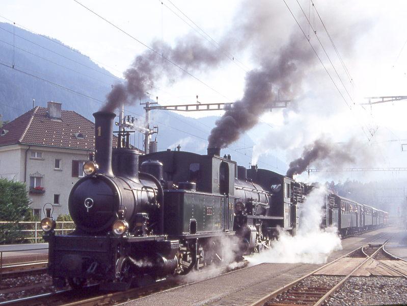 RhB Kursbuch-Dampfzug 6766 von Disentis nach Landquart vom 27.08.1995 in Domat-Ems mit Dampflok-Dreifachbespannung G 3/4 1 - G 4/5 108 - G 4/5 107 - B 2247 - D 4052I - B 2246 - A 1102 - B 2060 - B 2245 - B 2218 - B 2217. Hinweis: Aufnahme im Gegenlicht.

