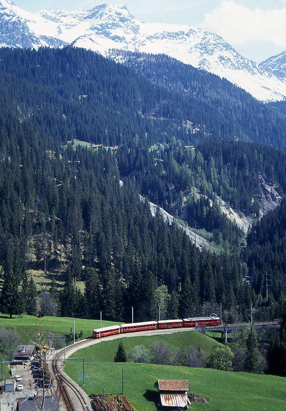 RhB Regionalzug 644 von Arosa nach Chur am 15.05.1994 Einfahrt Langwies mit ABt 1701I - B 2319 - DZ 4233 - ABDe 4/4 483II schiebender Triebwagen. Hinweis: Der talwrts fahrende Pendelzug hat soeben den Langwieser Viadukt verlassen und befindet sich in der Einfahrtskurve von Langwies, 200er-Teleaufnahme, noch Gleichstrombetrieb!