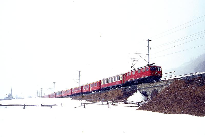 RhB REGIONALZUG 725 von St.Moritz nach Scuol am 08.03.1998 Ausfahrt S-chanf mit E-Lok Ge 4/4I 605 - As 1141 - A 1222 - A 1212 - A 1221 - A 1262 - A 1267 - A 1237 - D 4206. Hinweis: Dokumentation eines reinen 1.Klasse-Regionalzuges wegen Fahrzeugmangel an B-Wagen durch Groverkehr Engadiner Skimarathon.
