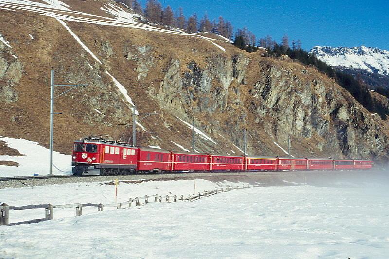 RhB Regionalzug 734 von Scuol nach St.Moritz am 26.02.1998 zwischen Samedan und Celerina mit E-Lok Ge 6/6II 706 - D 42xx - B 2343 - B 2345 - A 1233 - B 2325 - B 2265 - B 2468 - B 2331. Hinweis: ein um 4 B-Wagen verstrkter Regionalzug wegen bungslufer Engadiner Skimarathon, gescanntes Dia
