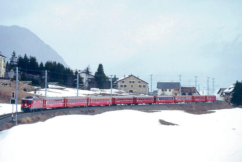 RhB REGIONALZUG 754 von Flablager (heute Haltestelle Marathon) nach St.Moritz am 08.03.1998 zwischen Zuoz und Madulain mit E-Lok Ge 4/4II 622 - B 2367 - B 2355 - A 1229 - B 2227 - B 2229 - B 2492 - B 2326 - B 2257 - B 2349. Hinweis: Planzug, der wegen Groverkehr gebrochen werden mute und nur im Oberengadin voll ausgelastet verkehrte. Pro Stunde knnen auf eingleisiger Strecke 6 Zugpaare abgewickelt werden mit Abtransport der etwa 20-Tausend Sportler beim Engadiner Skimarathon. Selbst die letzte Wagenreserve wird eingesetzt und die Zge verkehren in Maximallge der Kreuzungsgleise mit Lok und 9 Wagen. Eine Besonderheit gab es zwischen S-chanf und Einstiegstelle Flablager auf freier Strecke. Zur Beschleunigung des Betriebsablauf folgte ab S-chanf jeweils eine Lok auf Sicht den zugefhrten Leerzug aus St.Moritz nach. Diese Lok wurde in Flablager angekuppelt und als Triebfahrzeug zurck nach St. Moritz verwendet. Dafr wurde wegen der Zugkreuzung in S-chanf (zu kurze Kreuzungsgleise) die zufhrende Leerzuglok in Flablager abgekuppelt und folgte sofort den abgefertigten Zug auf Sicht hinterher bis S-chanf. Es gab keinerlei Versptung! 
