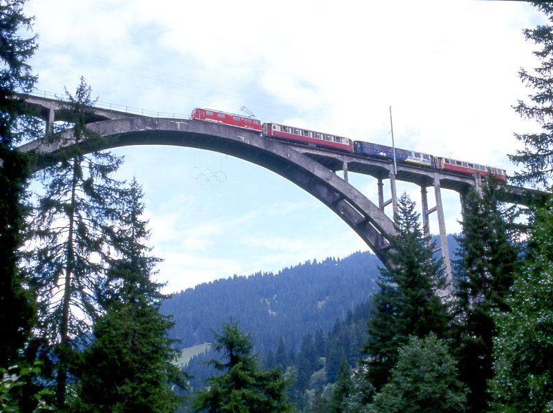 RhB Salon-Extrazug f�r GRAUB�NDEN TOURS 3629 von Chur nach Arosa am 30.08.1998 in auf Langwieser Viadukt mit E-Lok Ge 4/4I 610 - As 1141 - WRS 3821 - As 1154. Hinweis: erbaut 1914 in Stampfbetonbauweise, Br�ckenl�nge 284m, Spannweite des Bogen 100m, H�he 62m, Br�ckenmitte bei km 18,227. Damals waren erst vier Bahnbr�cken in Betonbauweise mit 50m Spannweite weltweit erstellt. Sand und Kies waren hier reichlich vorhanden, jedoch kaum Steine. Durch die Temperaturunterschiede Winter/Sommer dehnt sich die Br�cke in der Mitte um 7cm!  

