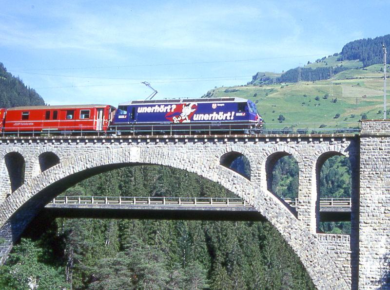 RhB Schnellzug 521 von Chur nach St.Moritz am 04.07.1999 auf Soliser Viadukt mit E-Lok Ge 4/4III 644 - D - B - ... Hinweis: Lok noch mit alter Werbung UNERHRT, Soliser Viadukt erbaut 1902 - Mitte bei Streckenkilometer 49,832 - Lnge 163,80m - Hhe 85,00m. Hier Blick von der alten Kantonalstraenbrcke.