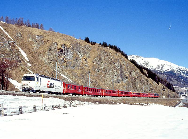 RhB SCHNELLZUG 531 von Chur nach St.Moritz am 26.02.1998 zwischen Samedan und Celerina mit E-Lok Ge 4/4III 643 - D - B - B - B - A - A - B - B. Hinweis: Lok mit Werbung EMS
