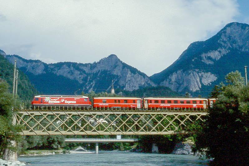 RhB Schnellzug 535 von Chur nach St.Moritz am 02.09.1997 auf Rheinbrcke bei Reuchenau mit E-Lok Ge 4/4III 641 - D 4217 - B 2379 - B 2343 - B 2374 - A 1225 - A 1239 - B 2438 - B 2441. Hinweis: Lok mit Werbung: BERNINA-EXPRESS, gescanntes Dia
