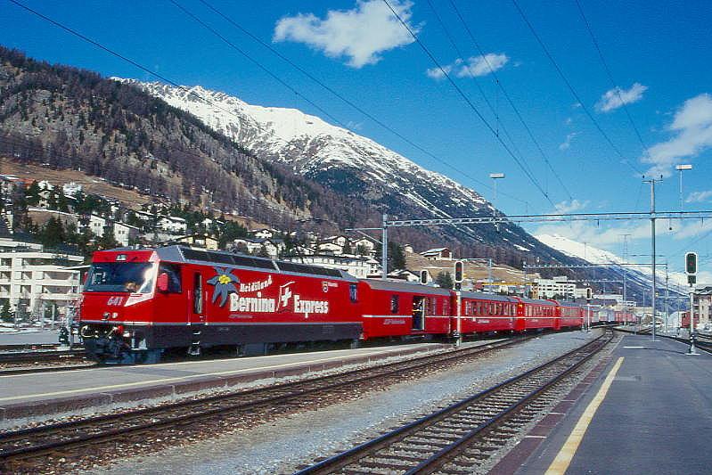 RhB Schnellzug 535 von Chur nach St.Moritz am 07.03.1998 Einfahrt Samedan mit E-Lok Ge 4/4III 641 - D 1216 - B 2358 - B 2377 - B 2391 - A 1228 - A 1241 - FO PS 4011 - As 1161 - WR 3811 - B 2326 - B 2257 - B 2349 - B 2269. Hinweis: Lok mit Werbung BERNINA-EXPRESS, gescanntes Dia
