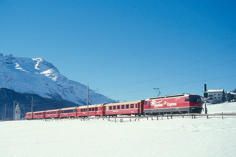 RhB Schnellzug 540 von St.Moritz nach Chur am 26.02.1998 bei Celerina mit E-Lok Ge 4/4III 641 - A 1263 - A 1283 - B 2493 - B 2379 - B 2360 - D 4223. Hinweis: Lok mit Werbung: Bernina-Express, gescanntes Dia

