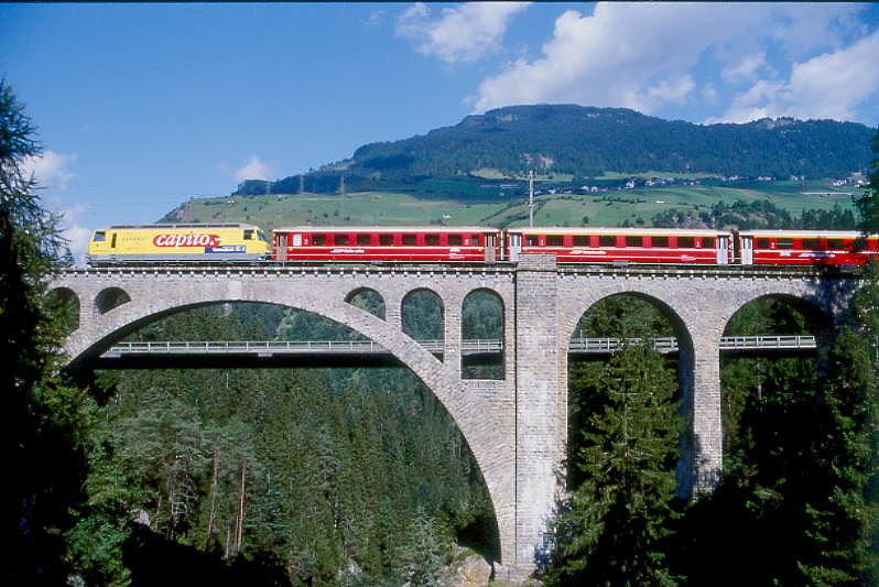 RhB Schnellzug 540 von St.Moritz nach Chur am 27.08.1998 auf Soliser Viadukt zwischen Tiefencastel und Thusis mit E-Lok Ge 4/4III 647 - B - 2x A - 3x B - D. Hinweis: Lok mit Werbung: Capito, gescanntes Dia
