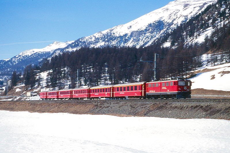 RhB Schnellzug 544 von St.Moritz nach Chur am 12.03.2000 zwischen Samedan und Bever mit E-Lok Ge 6/6II 705 - A 1269 - A 1233 - B 2431 - B 2362 - B 2356 - D 4224. Hinweis: gescanntes Dia
