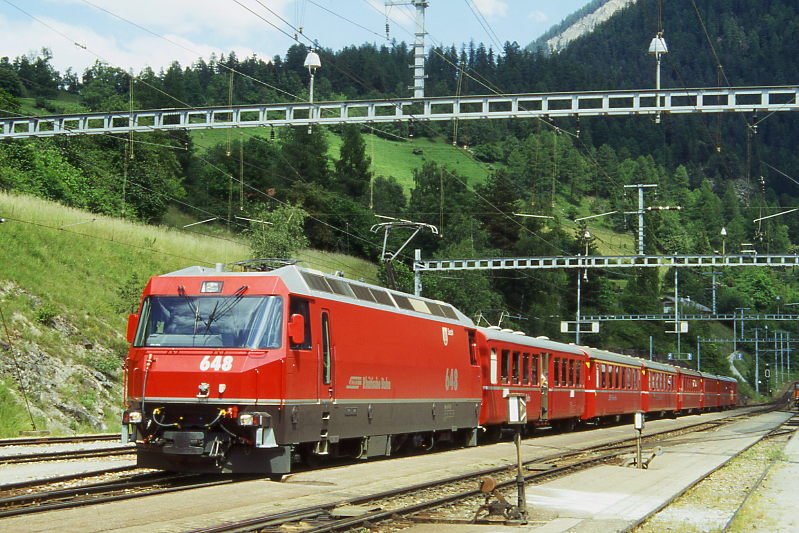 RhB Schnellzug 560 von St.Moritz nach Chur am 27.06.1995 in Filisur mit E-Lok Ge 4/4 III 648 - B 2325 - A 1234 - A 1230 - B 2380 - B 2429 - B 2375 - D. Hinweis: Lok noch ohne Werbung. hinter der Lok ist ein Mitteleinstiegs-Verstrkungswagen Baujahr 1948 im Schnellzug eingereiht, gescanntes Dia.
