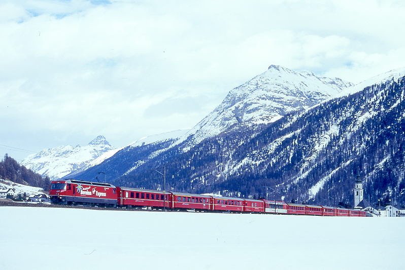 RhB Schnellzug 560 von St.Moritz nach Chur am 07.03.1998 im Val Bever zwischen Bever und Spinas mit E-Lok Ge 4/4 III 641 - B - 2x AB - D - FO PS 4011 - A 1241 - A 1228 - B 2391 - B 2377 - B 2358 - D 4216. Hinweis: Lok noch mit alter Werbung: BERNINA-EXPRESS, gescanntes Dia.
