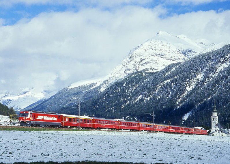 RhB Schnellzug 560 von St.Moritz nach Chur am 04.09.1999 im Val Bever zwischen Bever und Spinas mit E-Lok Ge 4/4 III 646 - A 1270 - B 2383 - B 2434 - A 1281 - A 1233 - B 2297 - B 2361 - B 2341 - D 4215. Hinweis: Lok mit kurzzeitiger Eigen-Werbung: RHTISCHE BAHN, gescanntes Dia.
