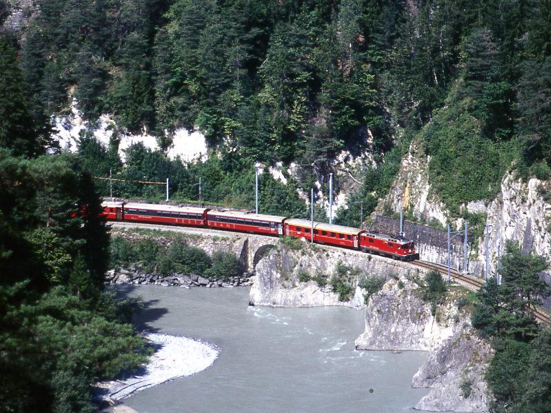 RhB Schnellzug GLACIER-EXPRESS B 902 von Zermatt nach St.Moritz vom 23.08.2000 in der Vorderrheinschlucht bei der Hochwassermarke zwischen Trin und Reichenau mit E-Lok Ge 4/4II 619 - A - WR 3817/3816 - A 1265 [Hilfsspeisewagen] - B - B - BVZ B - BVZ A - FO B - WR 3810ff - FO AS - BVZ AS - FO AS - FO AS - FO AS. Hinweis: 15-Wagenzug (Teil sichtbar). Fotostelle ber Bonaduz gut erreichbar, vom Parkplatz am Waldrand 15 Minuten.